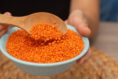 Hands Pouring Red Lentils into Bowl. Hands overflowing with vibrant red lentils over a bowl clipart