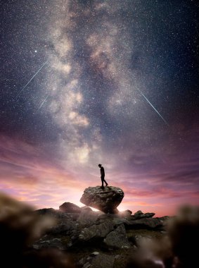 Samanyolu galaksisi alacakaranlıkta gökyüzüne yükselirken bir kayanın üzerinde duran bir adam. Fotoğraf bileşimi
