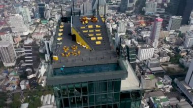 Çalışanlar cam zemini temizler ve ziyaretçiler için izleme alanını hazırlarlar. Bangkok şehir merkezinin havadan görüntüsü. Gökyüzü düzenleyicisi Kral Power MahaNakhon ve gözlem platformundaki insanlar üzerinde uçuyor..