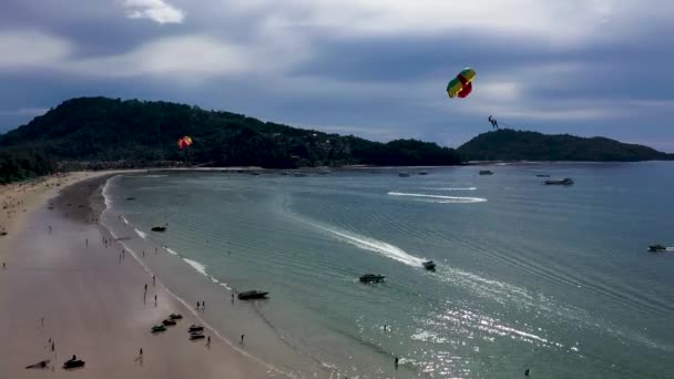 Nsanlar Denizin Arka Planına Bağlı Renkli Bir Paraşüt Üzerinde Uçuyorlar — Stok video