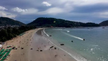 İnsanlar denizin arka planına bağlı renkli bir paraşüt üzerinde uçuyorlar. Phuket 'te aşırı boş zaman aktiviteleri. Parasailing.