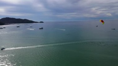 Patong, Tayland 'daki Patong Körfezi' nde paraşütçü, yolcu gemisi ve sürat teknesi ile bir kişi sahneyi paylaşıyor..