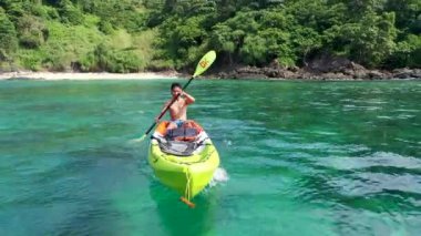 a young asian man enjoying kayak in the clear sea in Phi Phi Island, Thailand.