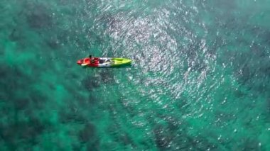 Aerial drone video of man enjoying sport kayak in tropical exotic landscape with crystal clear emerald sea.