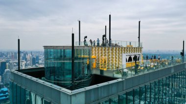 Bir grup insan ya da gezgin Bangkok Tayland 'da Mahanakhon Skywalk adlı yüksek binanın çatı katındaki manzarayı seyrediyorlar..