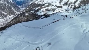 Riffelboden istasyonundan geçen buzullu ekspres tren ve kayakçı ile güzel bir Zermatt kayak merkezi. Matterhorn uçurumunun sihirli manzarasıyla kayak yapan insanlar. İnanılmaz İsviçre Alpleri.