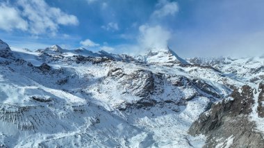 Pennine Alplerindeki Gornergrat dağ sırtı manzaralı otel, gözlemevi ve İsviçre 'nin Zermatt tepesinin arka planında bulunan demiryolu istasyonu karla kaplı..