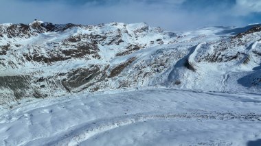 Mavi gökyüzü bulutu içinde kar dağı. İsviçre 'de Gorner Buzulu ve Gornergrat zirvesinin çarpıcı manzarası.