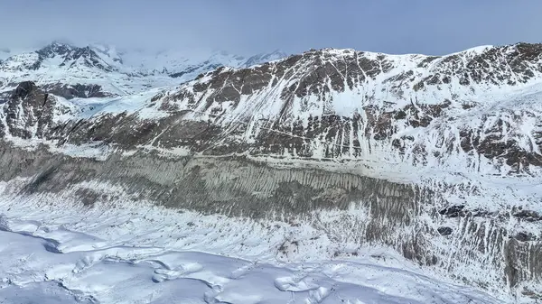 Mavi gökyüzü bulutu içinde kar dağı. İsviçre 'de Gorner Buzulu ve Gornergrat zirvesinin çarpıcı manzarası.