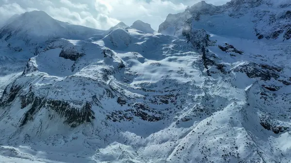 İsviçre 'nin karanlık engebeli dağının yamacında karla kaplı buzullar..