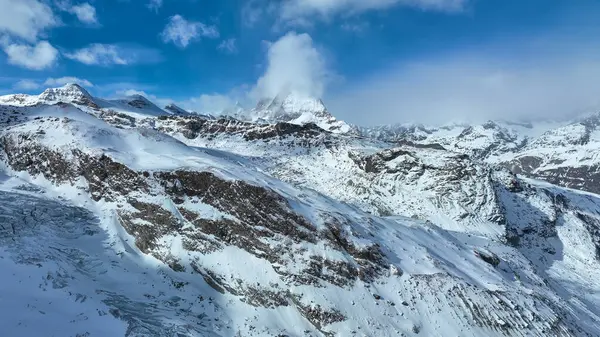 Kışın Matterhorn Dağı zirvesi. Karla kaplı yamaçlar ve mavi gökyüzü..
