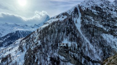 Dağ Hut Edelweiss kışın karla kaplı çatısı ile. Zermatt kasabasının üstündeki tepenin eteğinde. Arka planda Matterhorn olan dağların manzarası.