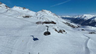 Teleferik teleferiği Piz Nair Dağı 'nın tepesine tırmanıyor. Alp yamacını geçiyor. Karlı bir dağ manzarasının nefes kesici manzarası. Görkemli, karla kaplı zirveleri uzaklara kadar uzanıyor..