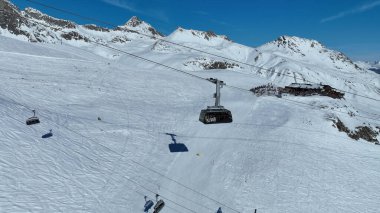 Teleferik teleferiği Piz Nair Dağı 'nın tepesine tırmanıyor. Alp yamacını geçiyor. Karlı bir dağ manzarasının nefes kesici manzarası. Görkemli, karla kaplı zirveleri uzaklara kadar uzanıyor..