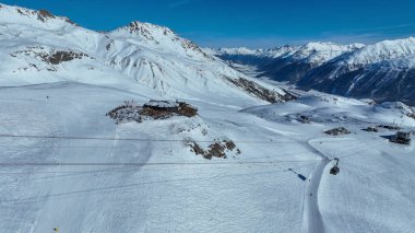 Piz Nair teleferiğine binen turistler dağ eteklerindeki karlı toprak üzerinde, Alp dağları altındaki St. Moritz Gölü ve Engadin Vadisi 'ndeki Pontresina köyü, Grisonlar, İsviçre.