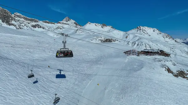 Piz Nair teleferiğine binen turistler dağ yamacındaki karlı dünyada gondola biniyorlar. Alp dağlarının altındaki St. Moritz ve Engadin Vadisi 'ndeki Pontresina köyü, Grisons, İsviçre.