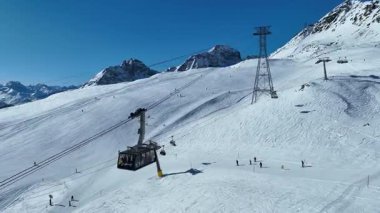 Piz Nair teleferiğine binen turistler dağ yamacındaki karlı dünyada gondola biniyorlar. Alp dağlarının altındaki St. Moritz ve Engadin Vadisi 'ndeki Pontresina köyü, Grisons, İsviçre