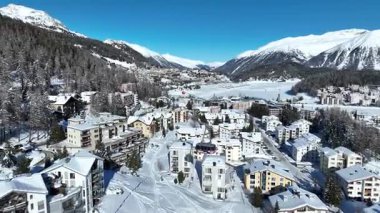 Kış ormanlarındaki dağlarda kablo tv arabası. Kulübeler kış kar ormanları boyunca gondol yolu boyunca ilerliyorlar. Dağları kaplayan beyaz bulutlar. İHA 'nın üst görüntüsü. Aziz Moritz.