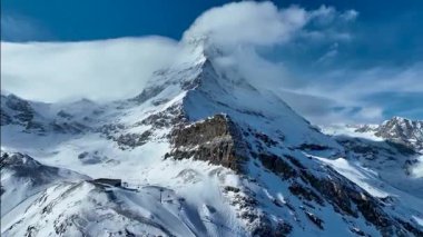 Güneşli bir günde, karlı Matterhorn zirvesinin manzarası. Mavi gökyüzü ve arka planda biraz bulut, İsviçre.