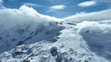 İsviçre Alplerinde güneşli bir günde karlı Matterhorn Dağı zirvesinin sinematik drone çekimi.