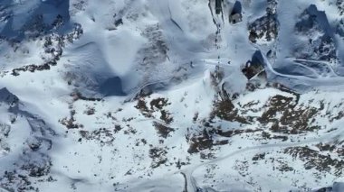 Kayakçılar karlı yamaçlarda güneşli bir günün tadını çıkarıyorlar ve arka planda İsviçre 'de teleferik var. Trockener Steg ve Schwarzsee 'nin kayak merkezi Zermatt' ta.