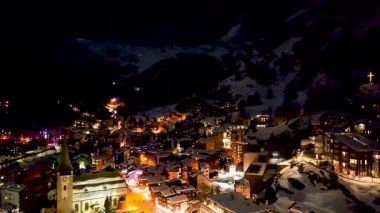 Tahta İsviçre evleri ve Zermatt 'ta karla kaplı bir katedral. Alpler, Zermatt, Avrupa 'daki resim gibi nehirleri olan tepelerdeki tipik İsviçre binalarıyla kayak merkezi..