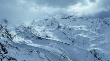 Kışın dağ sırtı, bulutlar, kar ve sisle.