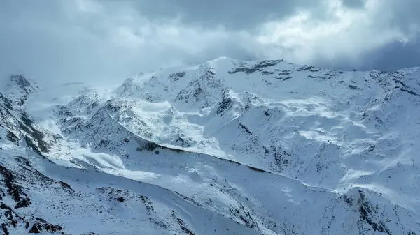 Kışın dağ sırtı, bulutlar, kar ve sisle.