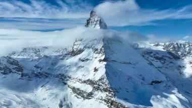 İsviçre Alpleri 'ndeki inanılmaz madde boynuzu ve etrafındaki dağlar fantastik bulut oluşumlarıyla.