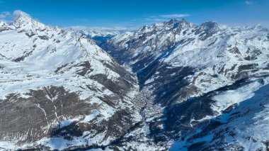 Karlı dağ vadisi ve kasaba. Hava aracı görüntüsü.