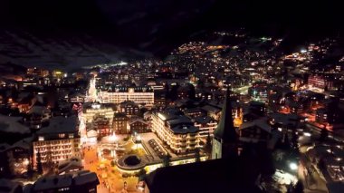 İsviçre Alpleri, İsviçre ve Avrupa 'daki güzel bahar gününde sakin köy ve St Mauritius kilisesine bakan Zermatt üzerinde gece uçuyor..