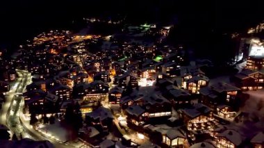 Zermatt 'ta karla kaplı tepelerdeki tipik renkli İsviçre evlerinin gece görüşü. Kış boyunca İsviçre 'nin Zermatt kentindeki Avrupa Alpleri' ndeki Kayak Kasabası 'nın yukarıdan görüntüsü.