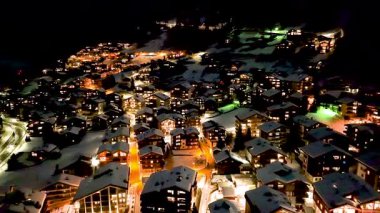 Zermatt 'ta karla kaplı tepelerdeki tipik renkli İsviçre evlerinin gece görüşü. Kış boyunca İsviçre 'nin Zermatt kentindeki Avrupa Alpleri' ndeki Kayak Kasabası 'nın yukarıdan görüntüsü.