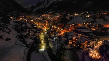 Zermatt 'ta karla kaplı tepelerdeki tipik renkli İsviçre evlerinin gece görüşü. Kış boyunca İsviçre 'nin Zermatt kentindeki Avrupa Alpleri' ndeki Kayak Kasabası 'nın yukarıdan görüntüsü.