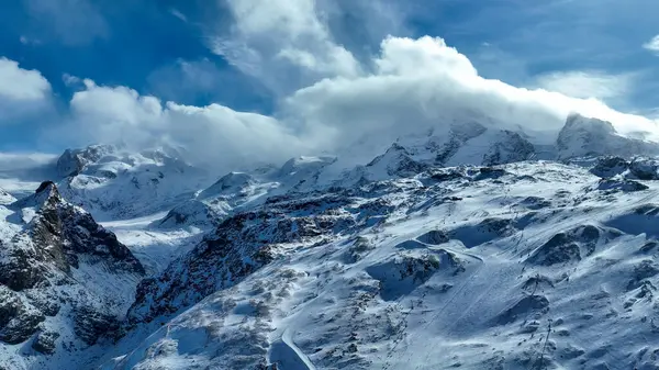 İsviçre, Zermatt 'ta engebeli bir zirvenin tepesinde, dik yamaçlarla, pürüzlü kayalarla ve açık mavi gökyüzüyle çevrili bir kayak kaldırma istasyonu..