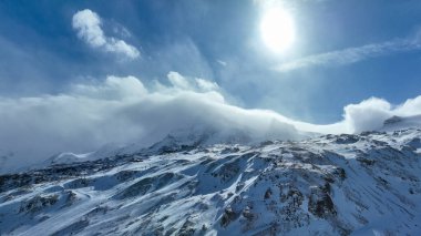 Karla kaplı bir dağ sırasına tırmanan bir kayak asansörünün ön planda daima yeşil ağaçların olduğu pitoresk bir kış sahnesi..