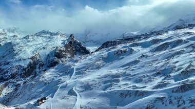 Karla kaplı bir dağ sırasına tırmanan bir kayak asansörünün ön planda daima yeşil ağaçların olduğu pitoresk bir kış sahnesi..