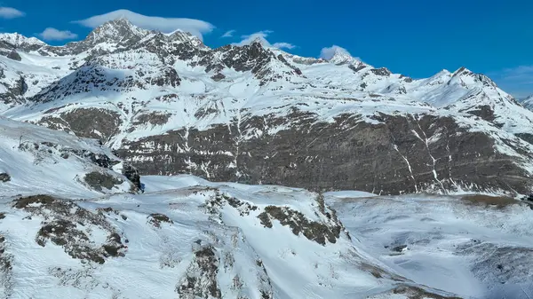 İsviçre Alpleri 'ndeki karla kaplı dağ zirveleri açık mavi gökyüzünün altında doğal güzellikleri ve dramatik dağlık manzaraları sergiliyor..