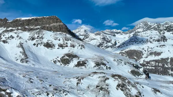 Görkemli kar tepeli dağ zirvesi berrak mavi gökyüzüne karşı dimdik duruyor. Kış manzarasının engebeli güzelliğini gözler önüne seriyor..