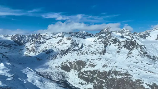 İsviçre Alpleri 'ndeki karla kaplı dağ zirveleri açık mavi gökyüzünün altında doğal güzellikleri ve dramatik dağlık manzaraları sergiliyor..