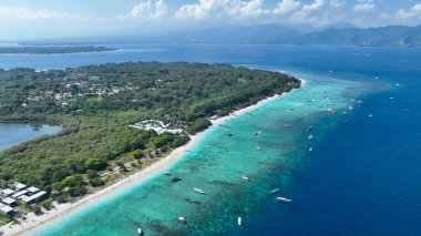 Beyaz kumlu plajı, mavi şeffaf suyu ve mercan resifleri olan tropikal bir ada. Hava saldırısı, sürat tekneleri, uzun kuyruklu botlar, Gili Trawangan Adası Endonezya.
