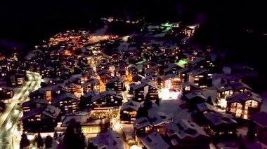 Zermatt 'ta karla kaplı tepelerdeki tipik renkli İsviçre evlerinin gece görüşü. Kış boyunca İsviçre 'nin Zermatt kentindeki Avrupa Alpleri' ndeki Kayak Kasabası 'nın yukarıdan görüntüsü.