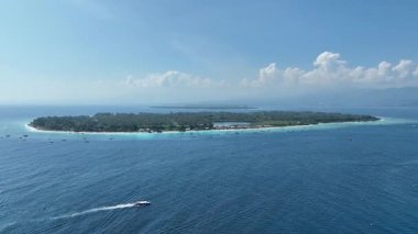 Mavi sularda yüzen bir teknenin havadan görünüşü ve Gili Meno yakınlarında beyaz baloncuklardan oluşan bir iz bırakıyor..