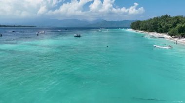 Gili Trawangan Adası kıyıları, kıyıya yakın temiz suyun tadını çıkaran turistler, bir sürü yerel tekne. İnsansız hava aracı kıyı şeridinde uçuyor..