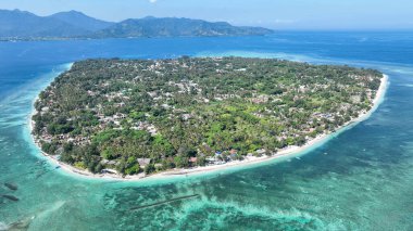 Gili Havası 'nın yemyeşil manzarası turkuaz sularla ve yakındaki dağların panoramik manzarasıyla beyaz plajlarla çevrilidir. Ada kaçamağı için ideal bir görüntü..