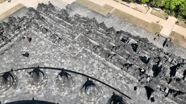 Bu hava detayı Borobudurs 'un üst teraslarını yakalıyor, tapınaklardaki ışık ve gölgelerin etkileşimini vurguluyor asırlık kabartmalar ve çevre yollar boyunca..