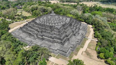 Borobudur zamansız bir mucize gibi duruyor, taş kolları ve stupaları yeşil araziye çarpıcı bir siluet oluşturuyor. Bu antik anıt her açıdan huşu ve yansımayı davet eder..