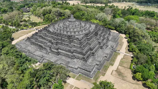 Borobudur zamansız bir mucize gibi duruyor, taş kolları ve stupaları yeşil araziye çarpıcı bir siluet oluşturuyor. Bu antik anıt her açıdan huşu ve yansımayı davet eder..