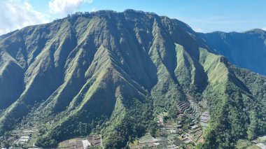 Dik, zümrüt yamaçlar Sembalun ufkuna hakim olurken, teraslı çiftlikler ve dağınık evler üste yuva yaparak Lombok 'taki doğanın ve yaşamın ahengini yakalıyor..