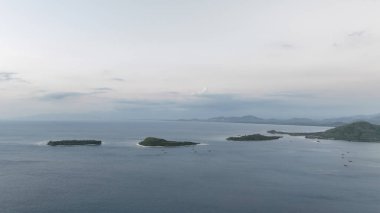 Gili adaları ve Lombok kıyı şeridinin hava görüntüleri. Adalar, uzak dağların arkaplanına karşı dizilmiş ve bölgenin çarpıcı bir perspektifini sunuyorlar..